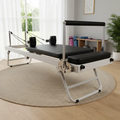 Pilates reformer machine in a home setting with a rug and window in the background